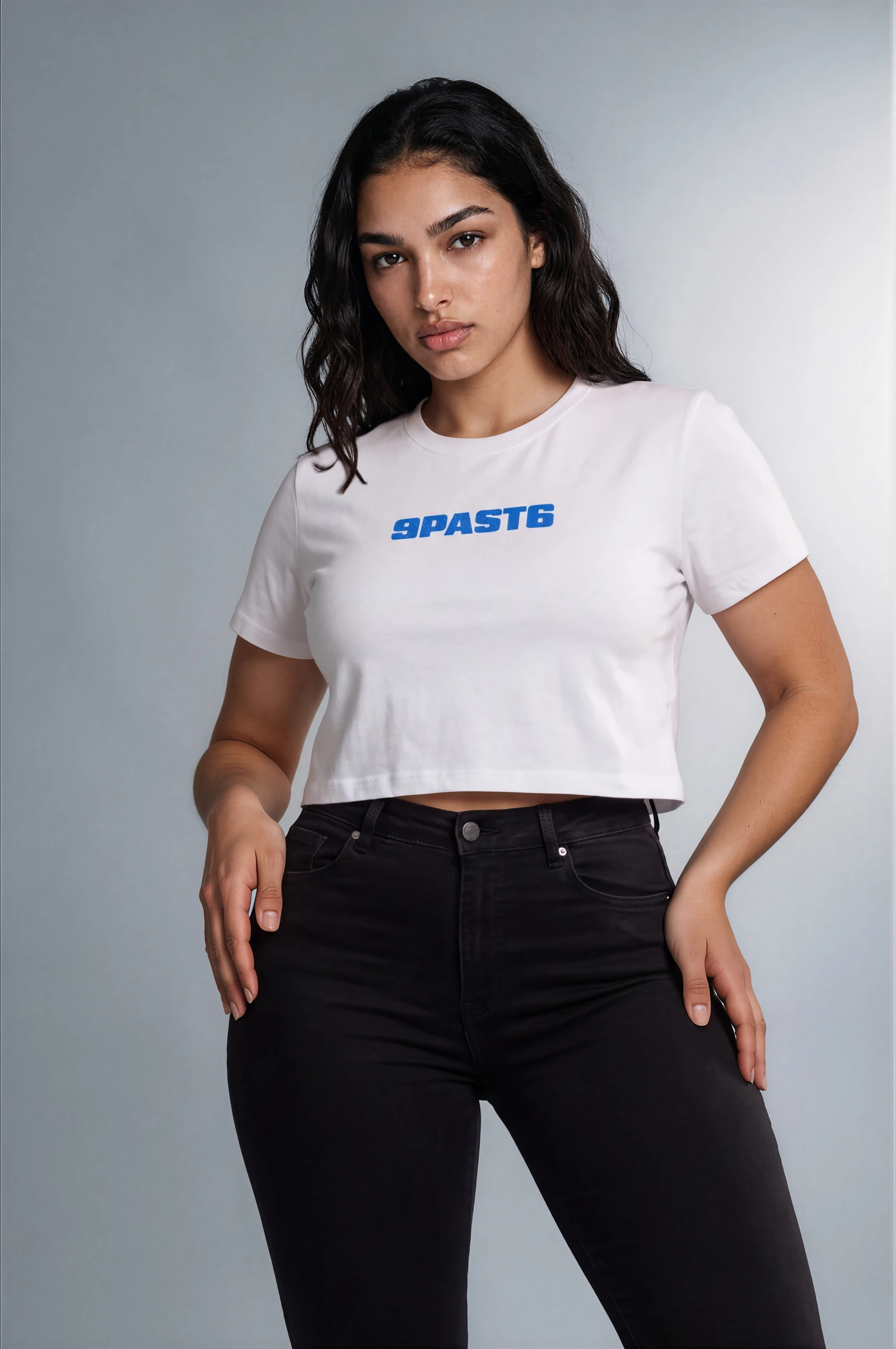 Female model imagery showing the same white cropped T-shirt with its blue 9PAST6 chest wordmark and black jeans.